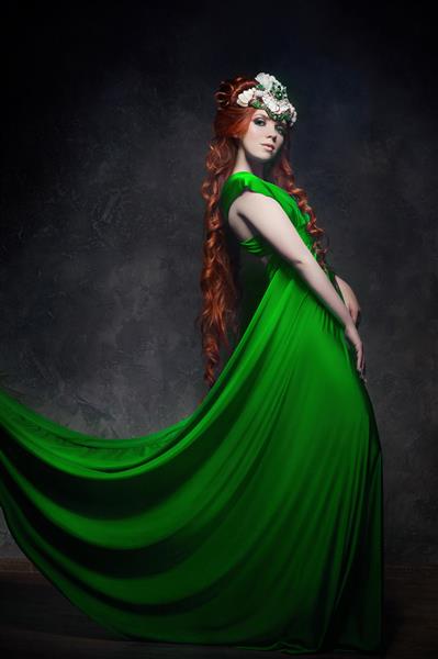 دختر مو قرمز ظاهر افسانه ای لباس بلند سبز آرایش روشن و مژه های بزرگ زن پری مرموز با موهای قرمز چشم های درشت و سایه های رنگی مژه های بلند ظاهر زیبا شاهزاده خانم در پس زمینه تیره