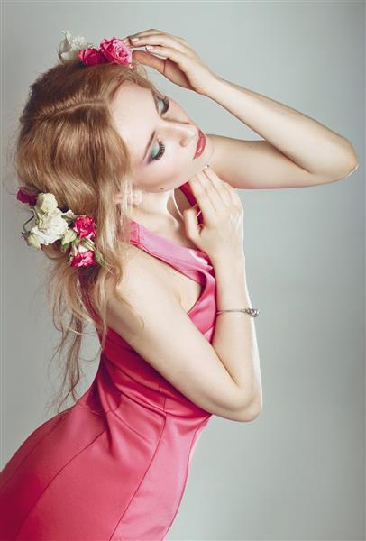 بلوند با گل در موهایش تصویر ظریف زیبا از یک زن استودیو در پس زمینه بژ عکس گرفته شده است آرایش عالی