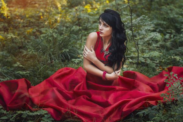 زن در لباس قرمز طولانی به تنهایی در جنگل