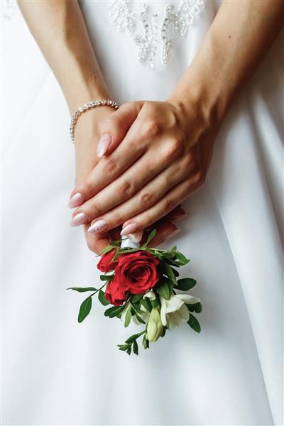 عروسی دسته گل عروسی از رزهای رنگارنگ در دست عروس
