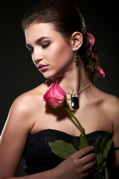 زن سبزه جذاب با گل رز در استودیو