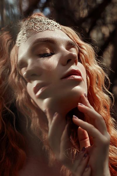پرتره افسانه ای از یک دختر مو قرمز در طبیعت با نوردهی دوگانه و خیره کننده دختر مو قرمز زیبا با موهای بلند در جنگل نگاه مرموز و چشمان درشت برگ و علف روی صورتش