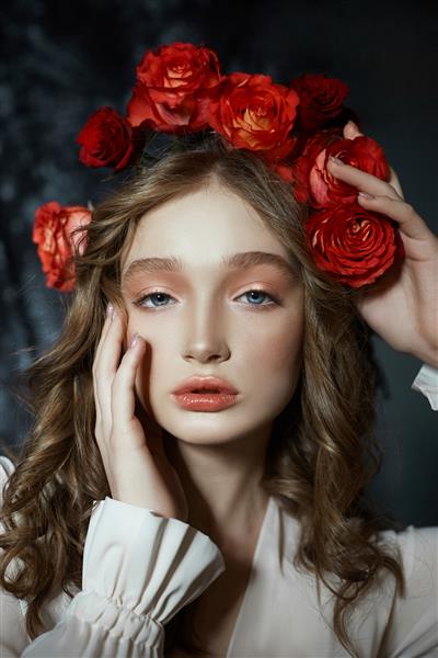 پرتره عاشقانه بهاری از یک زن جوان بلوند با تاج گلی از گل های رز قرمز