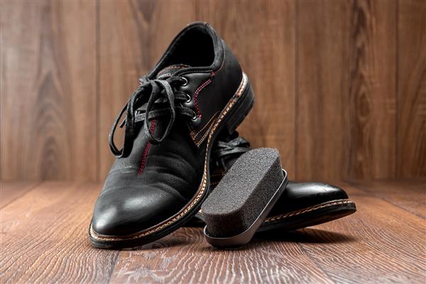 کفش های مشکی یک ثانیه کثیف و برس روی دیوار چوبی تمیز کنید مفهوم درخشش کفش مراقبت از لباس خدمات