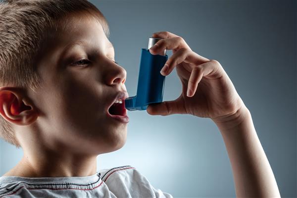 پرتره پسری که از دستگاه تنفسی آسم برای درمان بیماری های التهابی تنگی نفس استفاده می کند مفهوم درمان سرفه آلرژی بیماری های دستگاه تنفسی