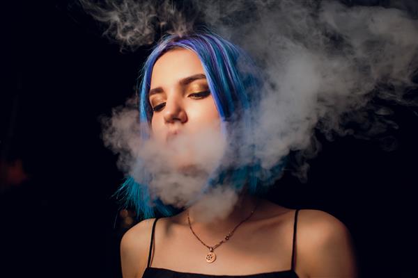 زن جوان در حال کشیدن سیگار الکترونیکی در پس زمینه سیاه