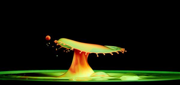 قارچ انفجاری قطره آب رنگی روی یک هنر مایع پشت زمینه