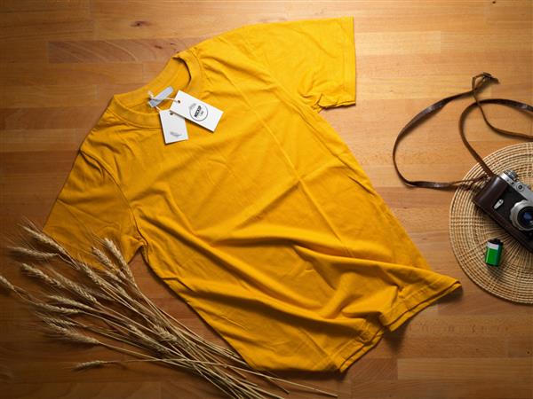 نمای بالای ماکت تی شرت زرد با برچسب قیمت ماکت روی میز چوبی