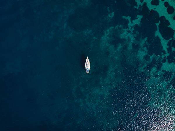 قایق تک در وسط دریای آبی شفاف