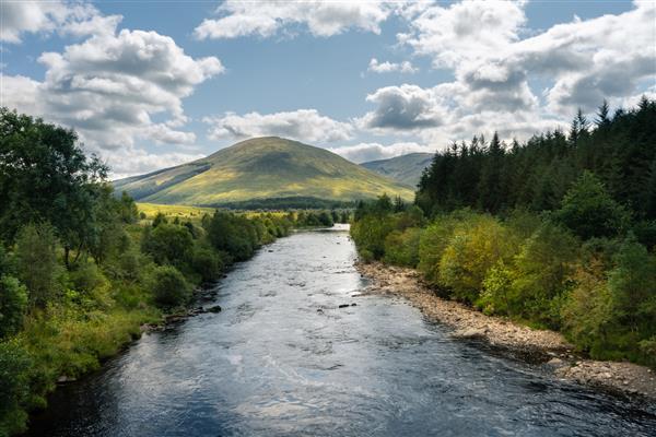 رودخانه ای که از میان درختان و کوه ها در اسکاتلند می گذرد