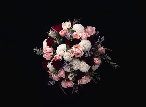عکس نزدیک از یک دسته گل مجلل از رزهای صورتی و گل محمدی سفید و قرمز در پس زمینه سیاه
