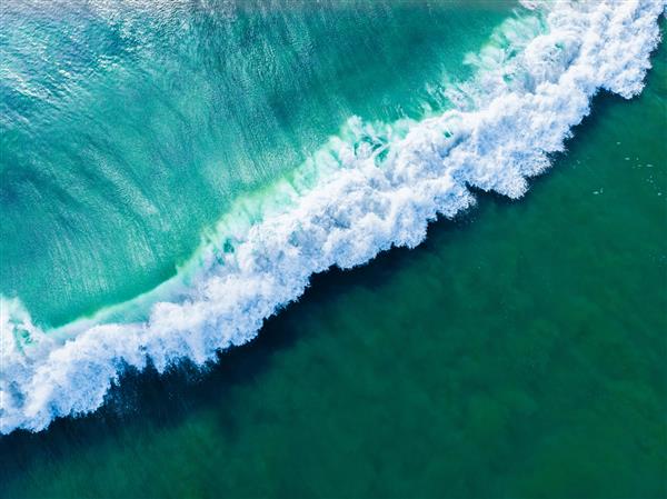 عکس هوایی بالای سر از دریای آبی مواج مناسب برای پس‌زمینه