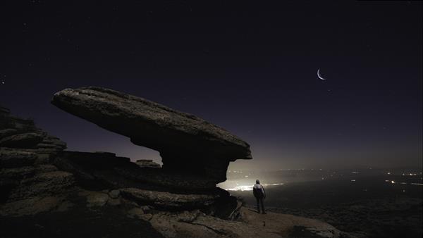 عکس زیبا از مردی که روی تپه ها زیر آسمان شب ایستاده است