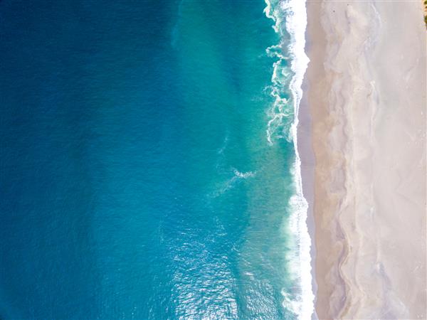 عکس با زاویه بالا از برخورد امواج اقیانوس با ساحل