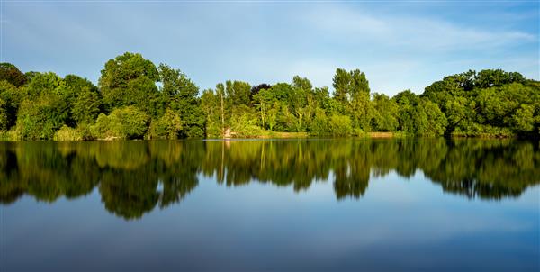 مناظر زیبای دریاچه با انعکاس درختان سبز اطراف