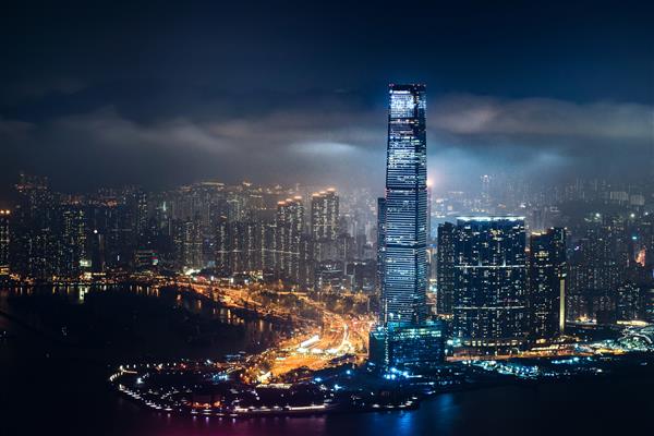 عکسی زیبا از ساختمان های بلند شهری زیر آسمان ابری در شب