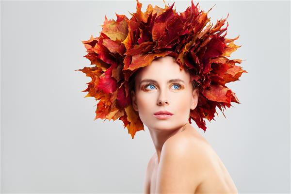 زن مدل مد پاییزی زیبا با برگ های افرا پاییزی روی سرش