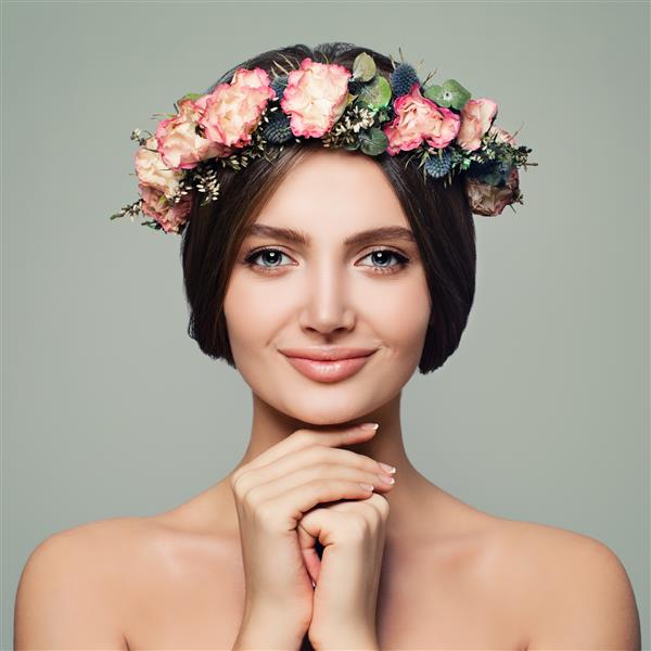 زن مدل جوان کامل با پوست سالم گل و دست های آراسته در پس زمینه آبی زیبایی جوان درمان صورت و مفهوم زیبایی
