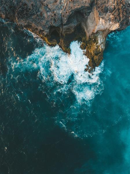 عکس هوایی عمودی از برخورد امواج دریا به صخره