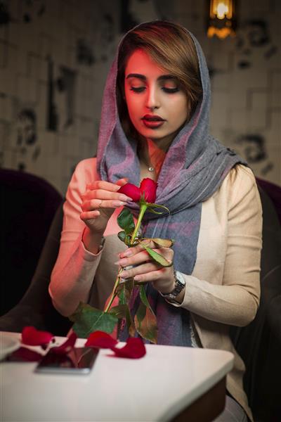 زن با حجاب با گل رز در رستوران