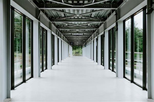 راهرو سفید با درهای شیشه ای و سقف فلزی در یک ساختمان مدرن