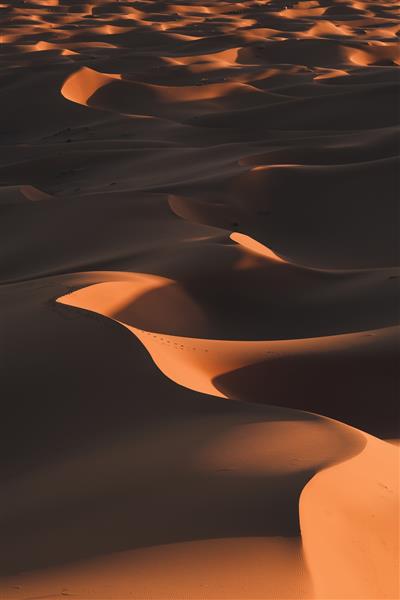 عکس عمودی از تپه های بیابانی خیره کننده زیر نور خورشید که در مراکش گرفته شده است