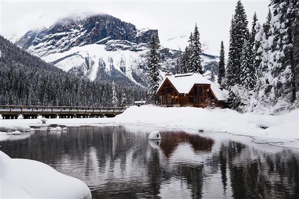 خانه چوبی کوچک پوشیده از برف در نزدیکی دریاچه زمرد در کانادا در زمستان