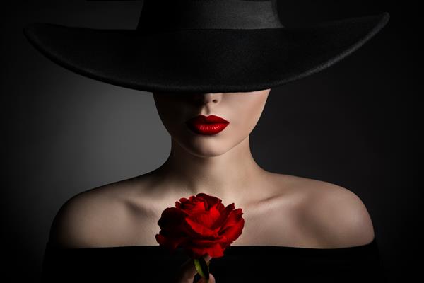لب های زن گل رز قرمز و کلاه مشکی پرتره زیبایی مدل مد شیک خانمی با کلاه لبه پهن روی زمینه تیره