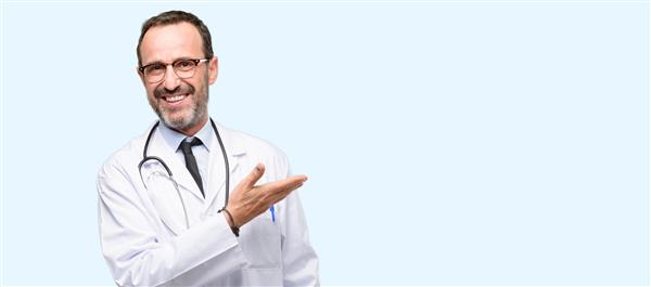 دکتر مرد ارشد متخصص پزشکی که چیزی را با دست خالی جدا شده روی پس‌زمینه آبی نگه می‌دارد