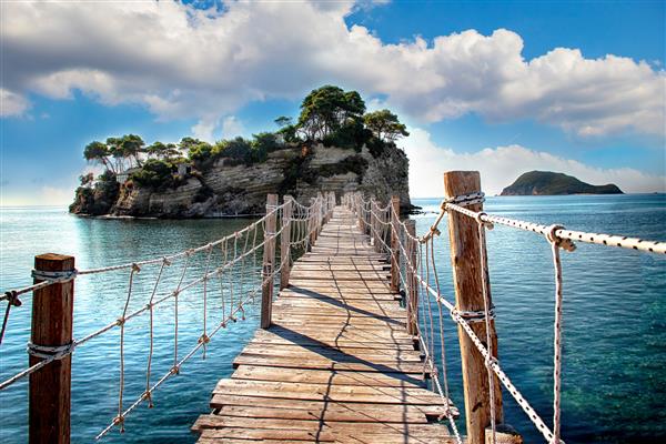 پل چوبی مشرف به دریا به جزیره ای با درختان نخل منتهی می شود این یک پل طنابی است در زاکینتوس یونان واقع شده است