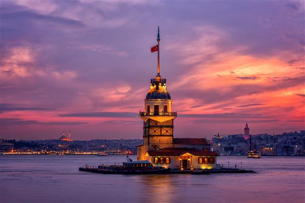 غروب آتشین آفتاب بر فراز بسفر با برج معروف Maidens Tower Kiz Kulesi که به نام برج Leander نیز شناخته می شود نماد استانبول ترکیه پس زمینه سفر منظره برای کاغذ دیواری یا کتاب راهنما