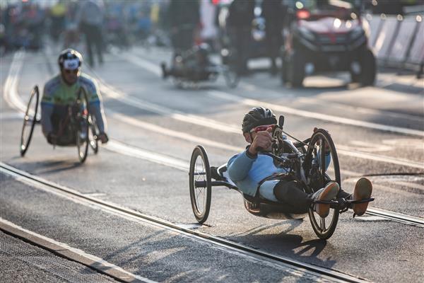 ورزشکار معلول با ویلچر ورزشی در حین دوی ماراتن ورزش حرفه ای معلولان