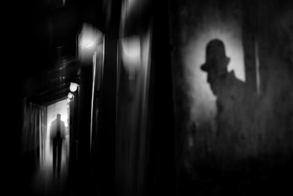 سیلوئت مردی با کت و کلاه در کوچه ای تاریک در شبی بارانی موضوع خشونت و ظلم اثر تاری