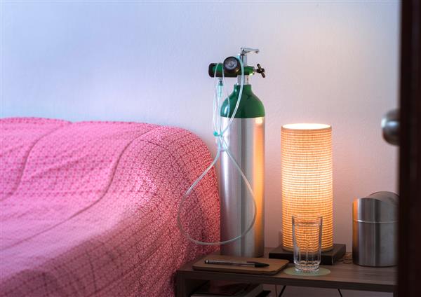 سیلندر اکسیژن با کانول روی میز خواب در کنار تخت