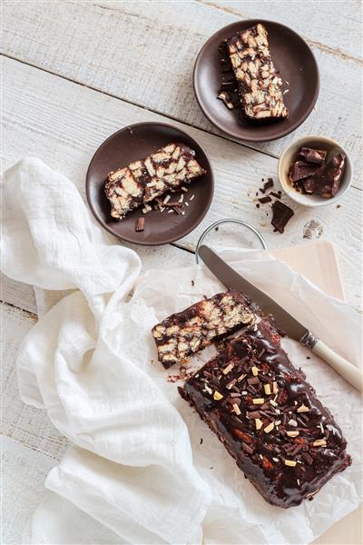 کیک بیسکویتی شکلاتی خانگی بدون پخت روی میز چوبی سفید کیک تنبل یا کیک موزاییکی یا سالامی شکلاتی به سبک تخت