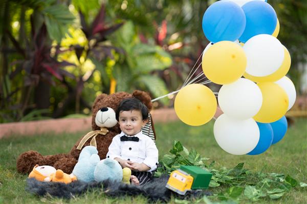 کودک از بازی با عروسک و اسباب بازی های نشسته در باغ خوشحال است
