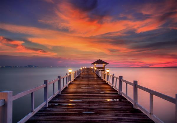 پل چوبی در بندر جزیره ساحلی بین طلوع خورشید