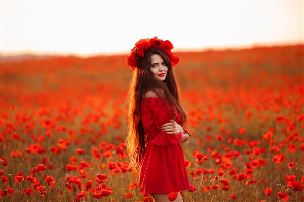 سبزه زیبا در مزرعه خشخاش قرمز پرتره دختر نوجوان خندان شاد با تاج گل روی سر که در پس زمینه طبیعت گل های خشخاش لذت می برد زن بی خیال