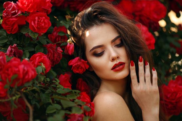 پرتره بیرون از خانه از زن زیبای طبیعی با گل رز قرمز زن شهوانی با گل های رز در مو سبزه زیبا با آرایش در پارک شکوفه غروب آفتاب اشتیاق و بیان سبک فلامنکو اسپانیایی