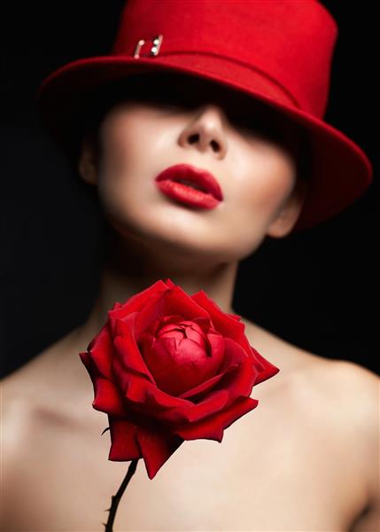 زن زیبا با کلاه پشت رز قرمز دختر دوست داشتنی با آرایش و پرتره گل