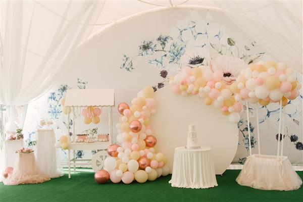 یک مهمانی زیبا تزئین شده با بادکنک در یک چادر سفید بزرگ با منطقه عکس پذیرایی و آب نبات