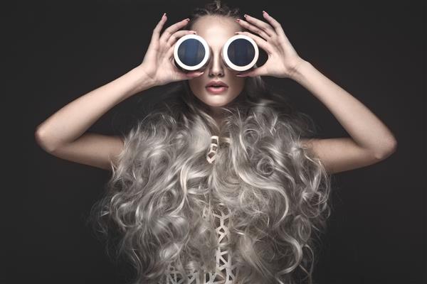 دختری زیبا با لباس هنری و مدل موی آوانگارد با محصولات آرایشی در دست صورت زیبایی عکس های گرفته شده در استودیو