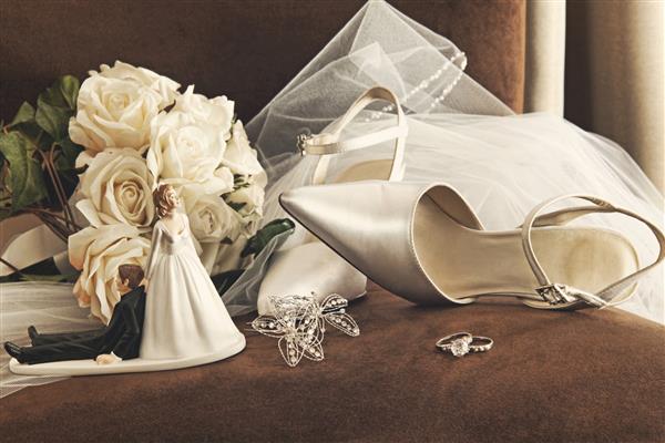 دسته گل رز سفید حلقه و کفش عروسی ساتن روی صندلی