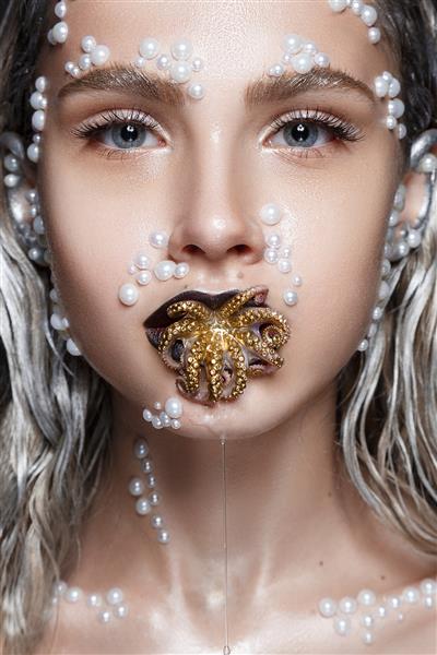 پرتره زن زیبا با آرایش هنری مهره های مروارید روی صورت و اختاپوس طلایی در دهان