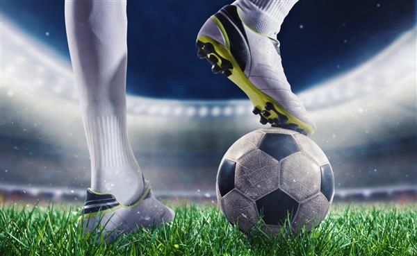 بازیکن فوتبال با توپ فوتبال در زمین چمن استادیوم آماده برای مسابقه