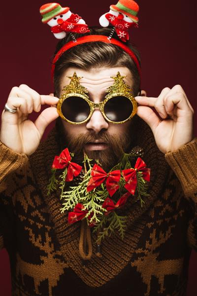 مرد ریشو بامزه در تصویر سال جدید به عنوان بابا نوئل با تزئینات روی ریش خود جشن کریسمس