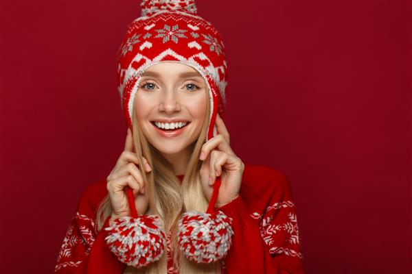 دختر بلوند زیبا در تصویر سال جدید با کلاه گرم و ژاکت صورت زیبایی با آرایش جشن عکس گرفته شده در استودیو