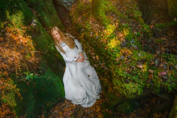 زن جوان زیبا با لباس سفید در وسط یک جنگل