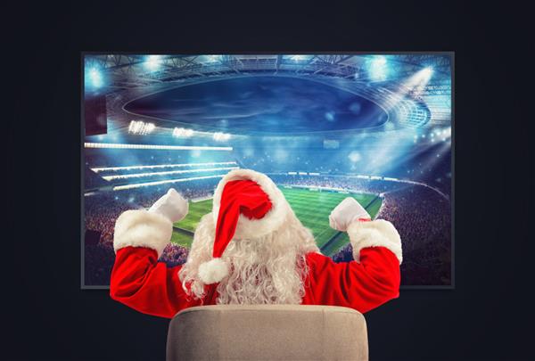 هوادار شاد فوتبال بابا نوئل در حال تماشای یک بازی از تلویزیون است
