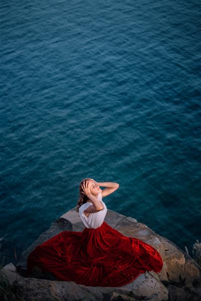 دختر زیبا با لباس قرمز در زمینه دریا